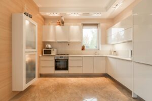 Stylish interior of kitchen with white cupboards and built in oven and stove under lamps on ceiling